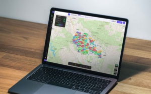 TopHap desktop application displayed on a laptop, showing map-based property search with advanced filters, listing markers, heat-map analytics, and regional real estate data.